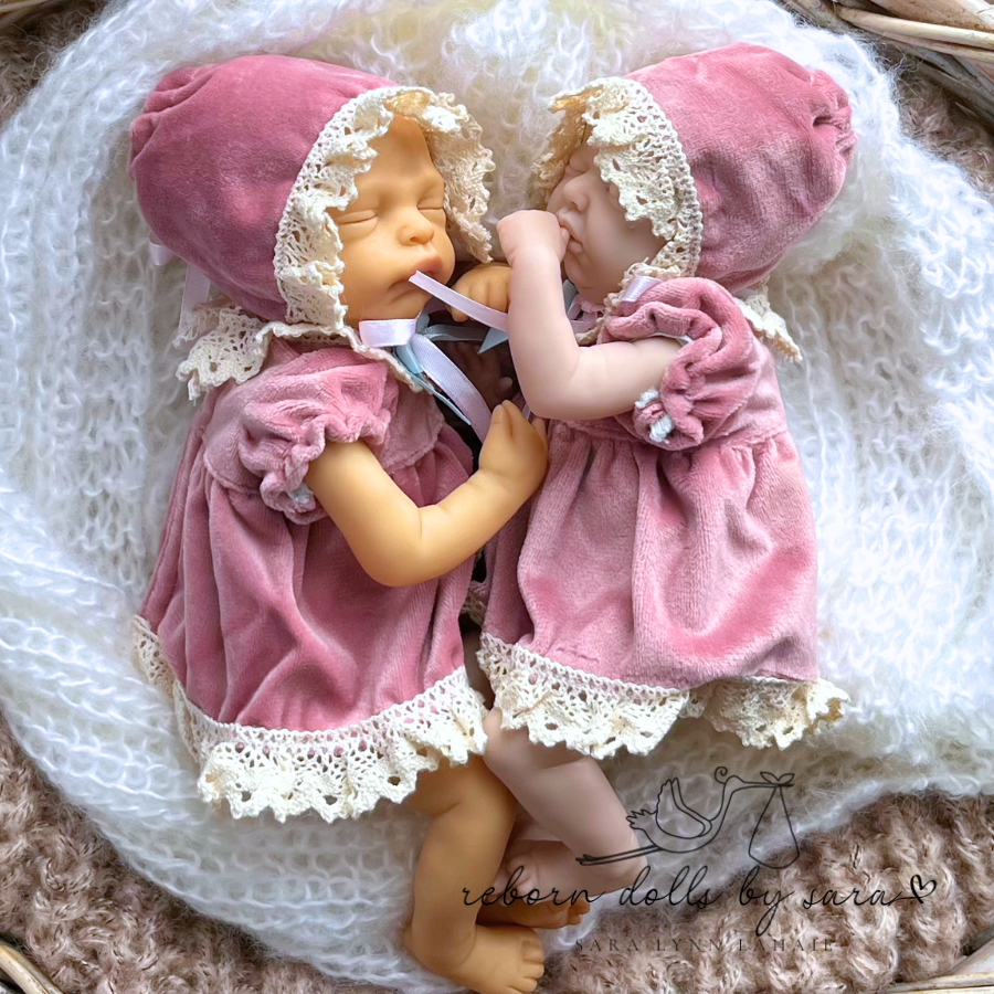 Two mini micro reborn dolls wearing miniature reborn doll dresses clothing.
