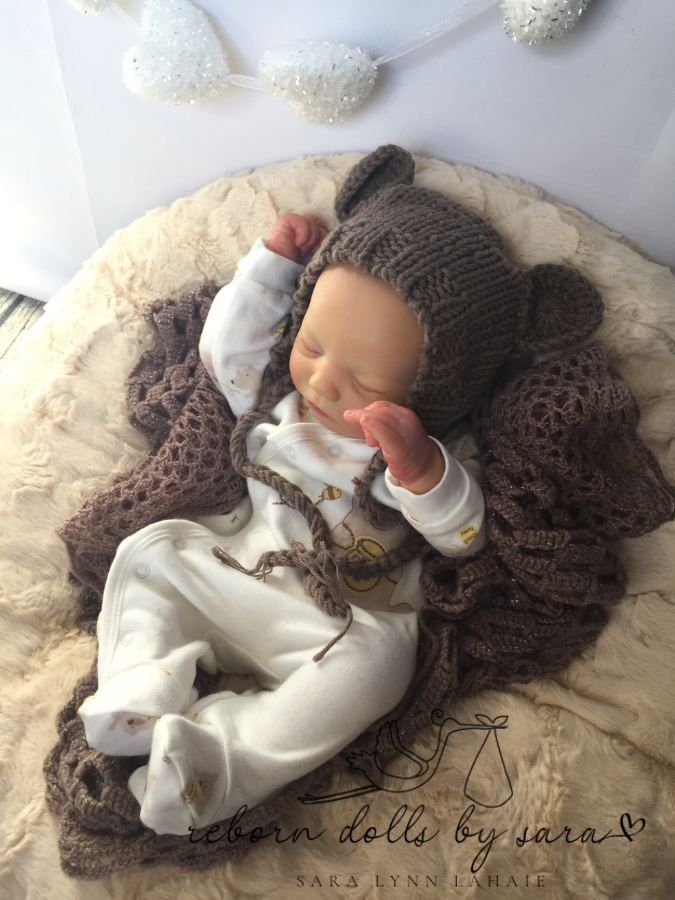 Reborn doll Realborn sleeping Zuri by Bountiful baby wearing the brown Lovey hand knitted newborn baby bear hat with matching teddy.