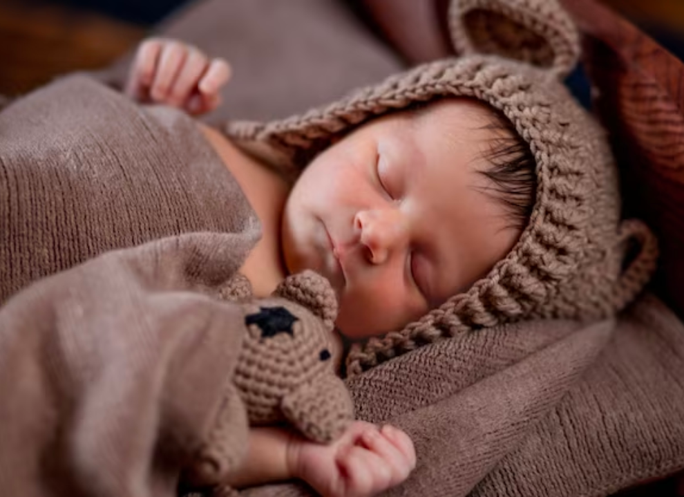 Newborn baby boy wearing the brown Cutie Pie Crochet Newborn Baby Bear Bonnet with Matching Stuffy