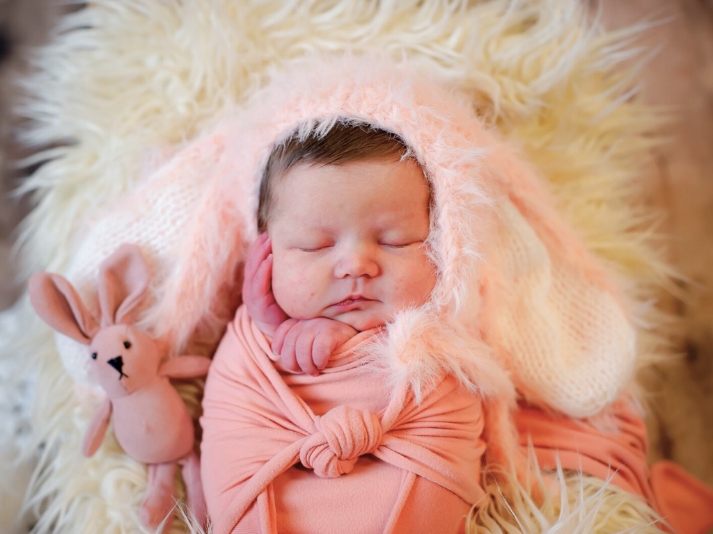 Newborn baby girl wearing the pink floppy eared fuzzy knitted mohair baby bunny bonnet for newborn photography, reborns, babies, and baby dolls.