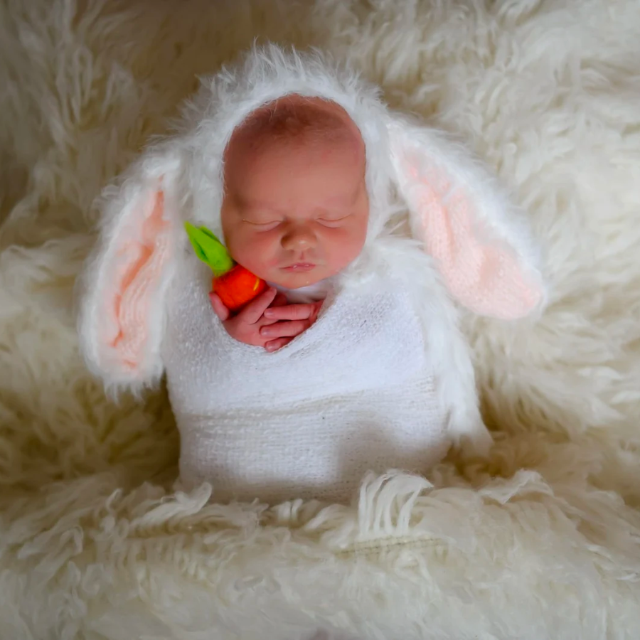 Newborn baby wearing the white and pink floppy eared fuzzy knitted mohair baby bunny bonnet for newborn photography and baby dolls.