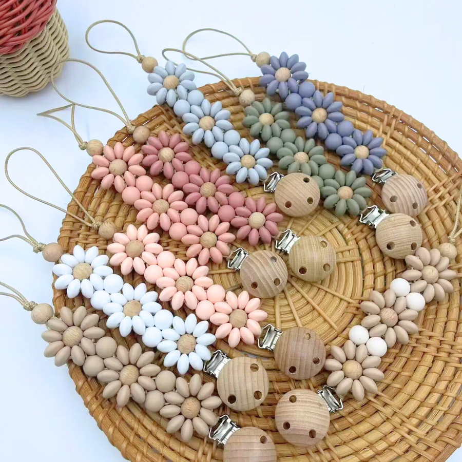 9 Boho baby pacifier clips in the shapes of flower daisies made of silicone beads on wooden clips with wooden beads coloured in pink, blue, white and neutral brown for reborn dolls.