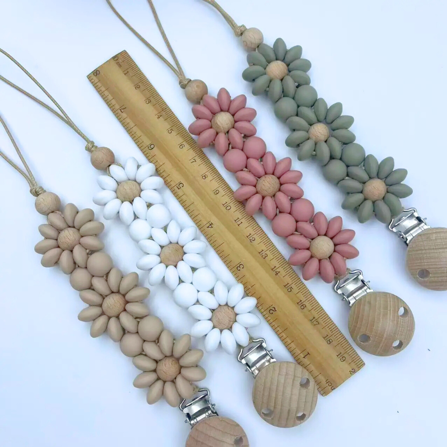 Boho baby pacifier clips in the shape of a daisy flower. Made of silicone saucer beads on a wooden clip with wooden beads for reborn dolls.Tan, white, pink and sage green.