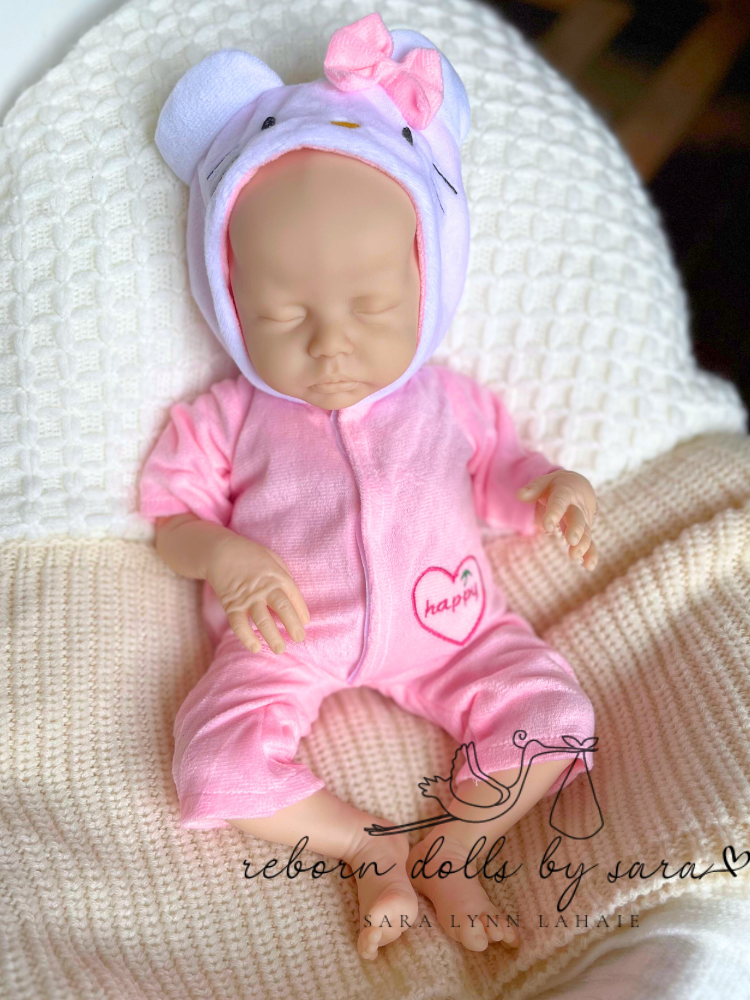 Preemie reborn doll 17" Delilah by Nikki Johnston wearing a pink Hello Kitty Dreamwear Hooded Romper from Reborn Dolls by Sara.