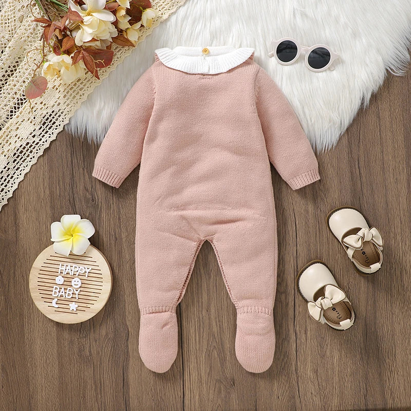 Shows the back of a Pink footed cable knit romper for reborn dolls with white Peter Pan collar and white princess crown on the chest with a pink heart in the centre.