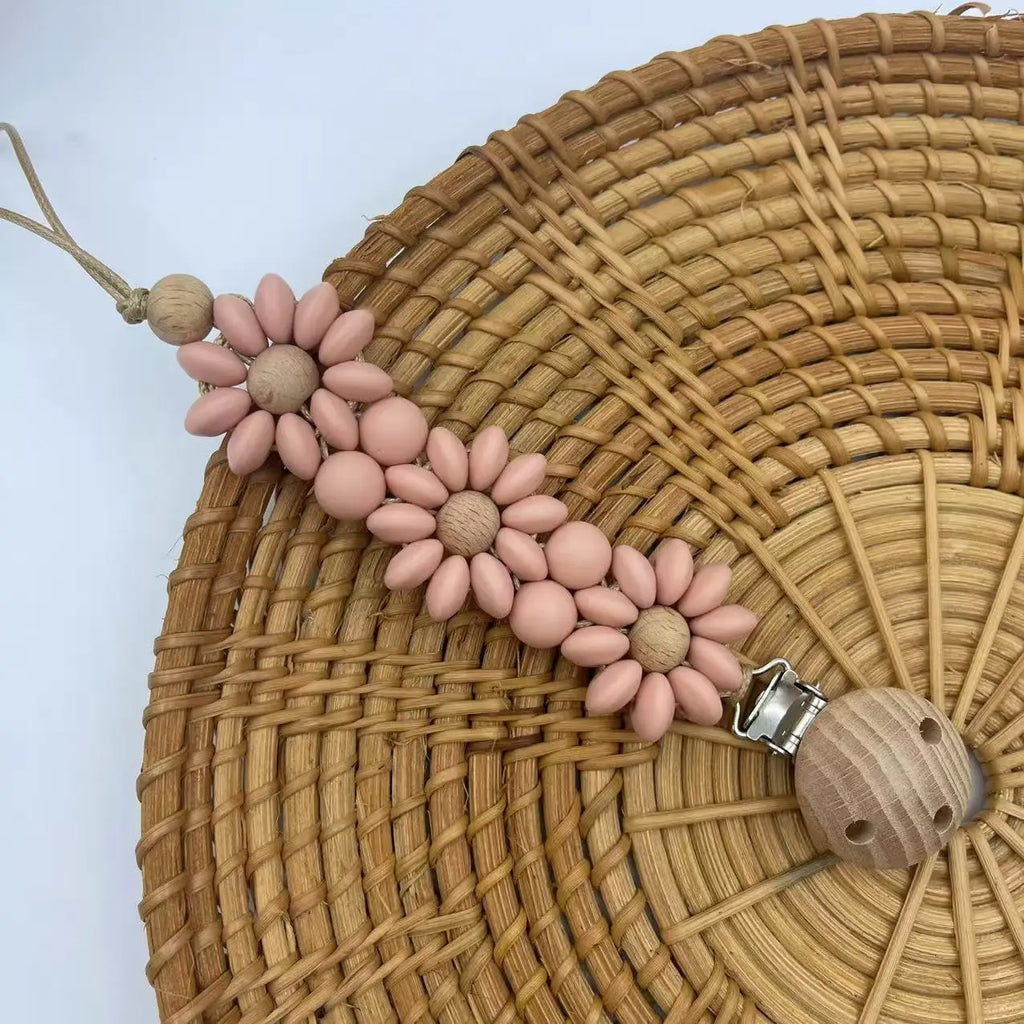 Light pink Boho baby pacifier clip in the shape of a daisy flower. Made of silicone saucer beads on a wooden clip with wooden beads for reborn dolls.