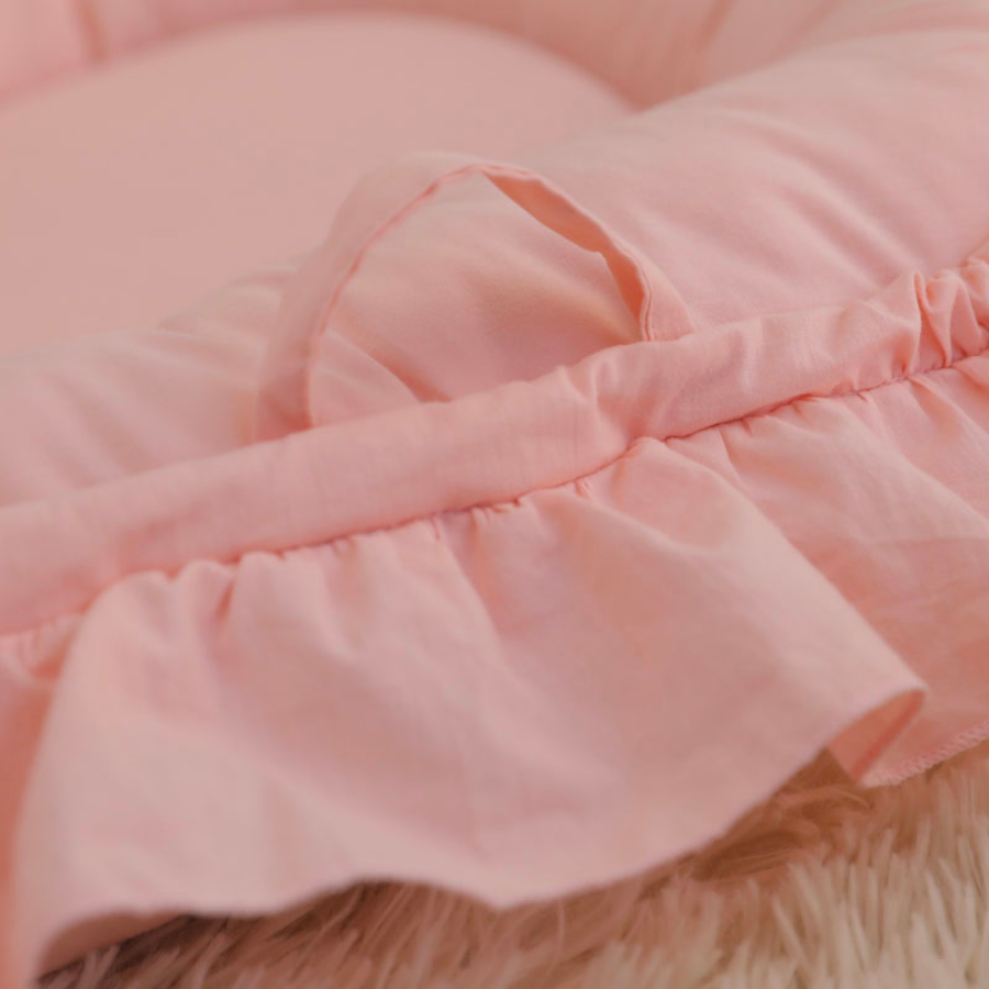 Pink handles on the shooting star boho baby nest with ruffles for newborn babies and reborn doll displays.
