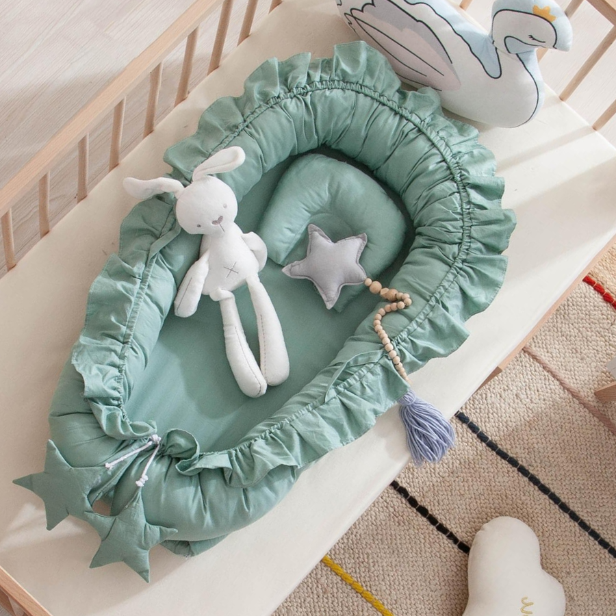 Sage green shooting star boho baby nest with ruffles for newborn babies and reborn doll displays.