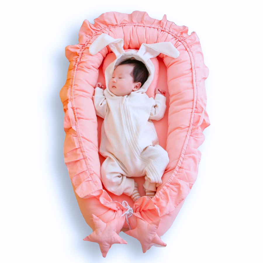 Newborn baby in a pink shooting star boho baby nest with ruffles for newborn babies and reborn doll displays.