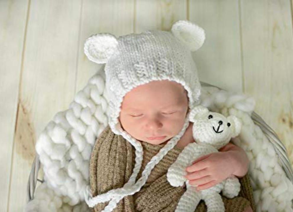 Newborn baby boy wearing the ivory white Lovey hand knitted newborn baby bear hat with matching teddy.