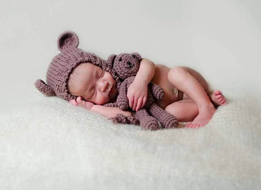 Newborn baby boy wearing the brown Lovey hand knitted newborn baby bear hat with matching teddy.