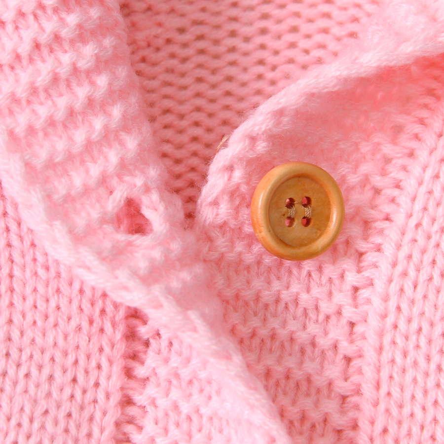 Close-up of the buttons and sleeve cuffs on a pink knitted bear romper for reborn dolls.