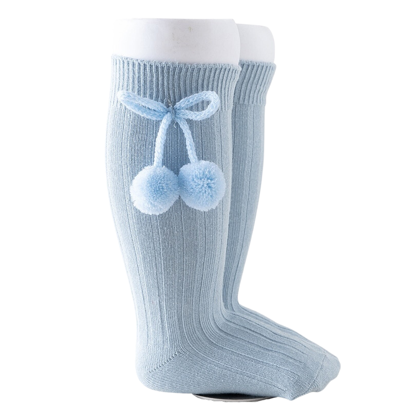 Light dusty powder blue knee-high Spanish baby socks with pompoms for reborn baby dolls boys and girls.