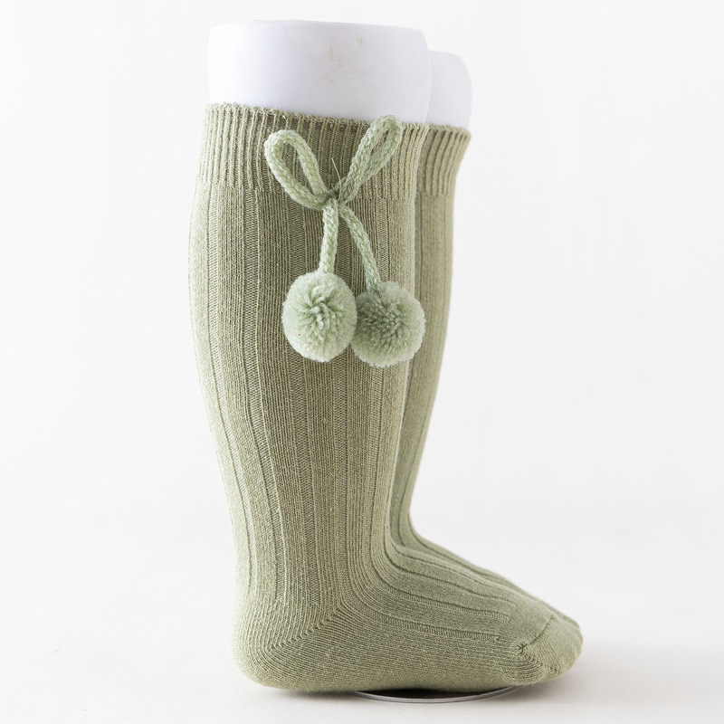 Sage green knee-high Spanish baby socks with pompoms for reborn baby dolls boys and girls.