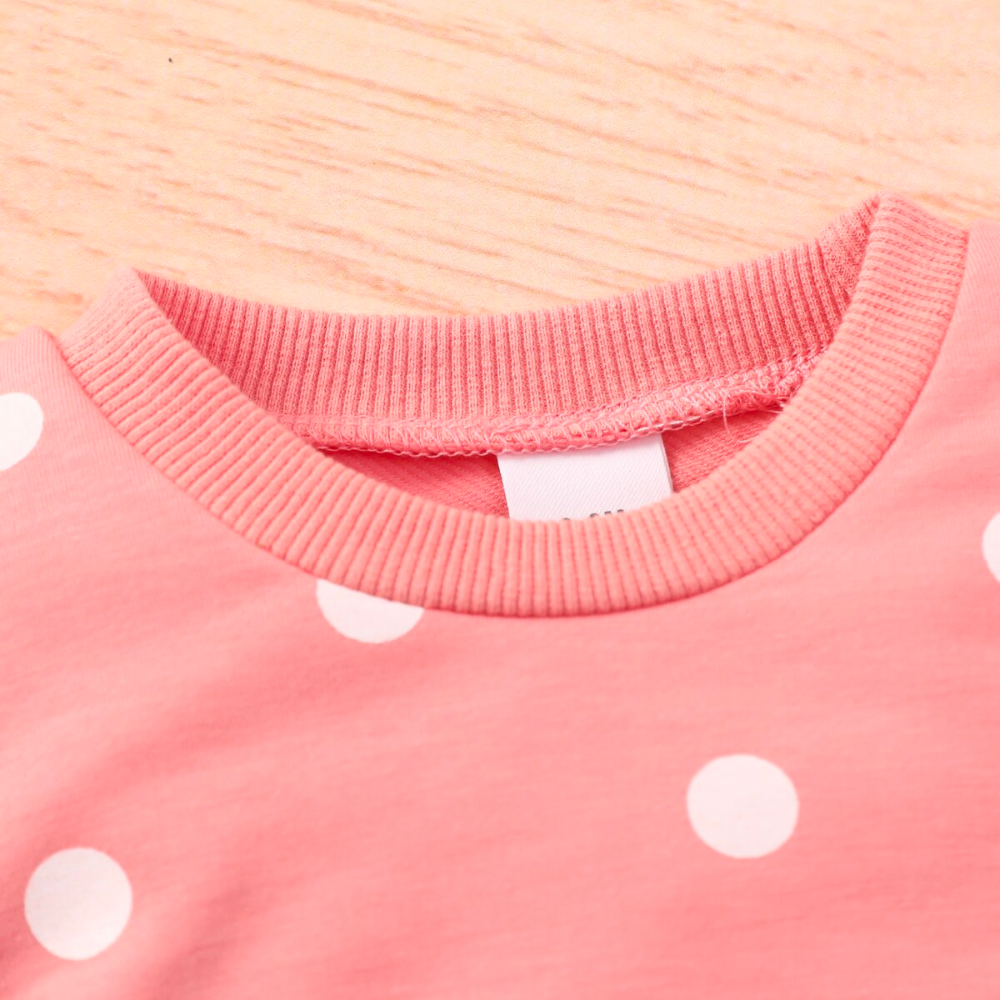 Close-up of the crewneck on a Pink jogging suit with white polka dots for newborn babies and reborn baby dolls.