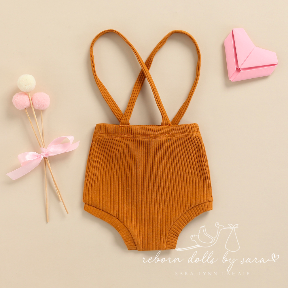 Back of a pair of terra cotta ribbed boho baby bloomers with suspenders for reborn baby dolls.