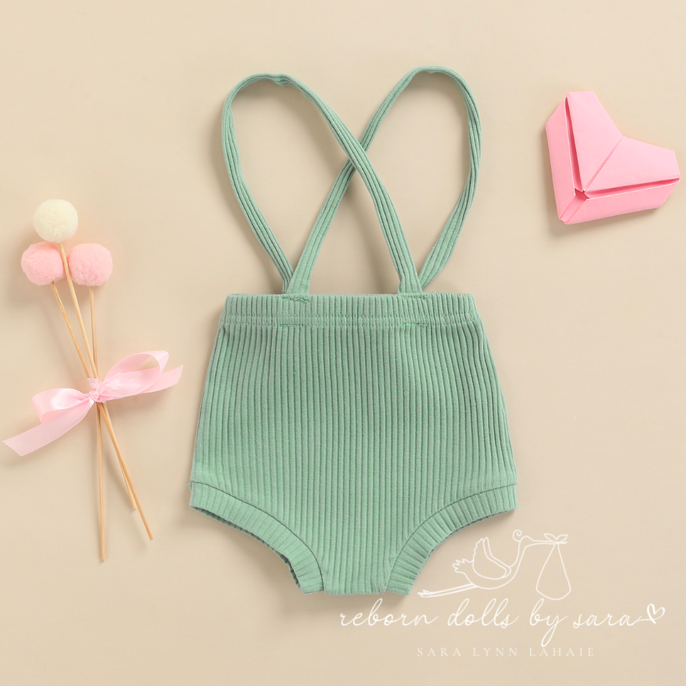 Back of a pair of sage green ribbed boho baby bloomers with suspenders for reborn baby dolls.