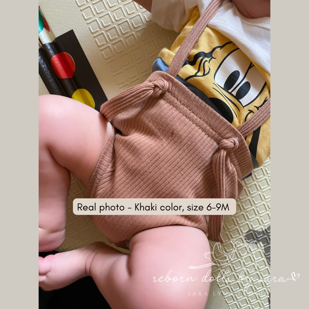 Baby wearing a pair of 6-9M khaki ribbed boho baby bloomers with suspenders for reborn baby dolls.