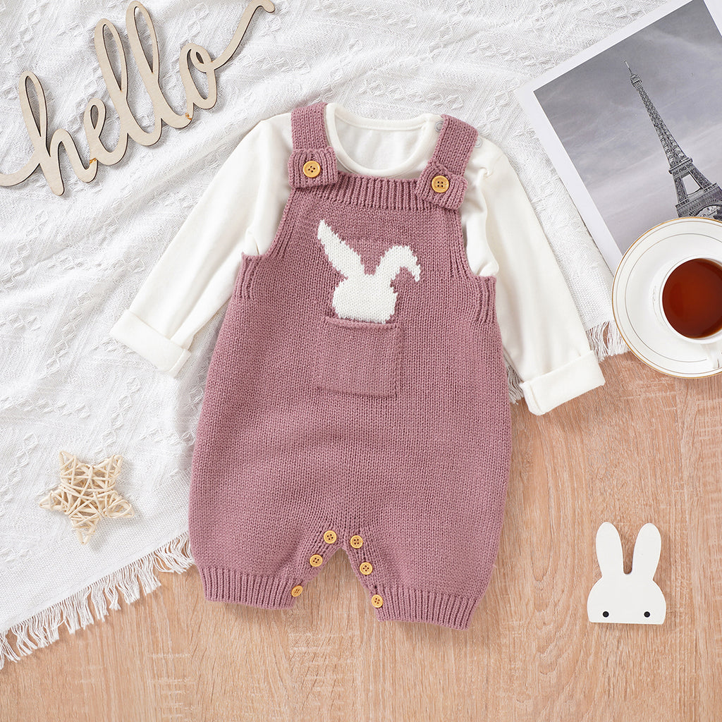 Blush Pink knitted overall shorts for reborn dolls with a white silhouette of a bunny rabbit sticking out of the pocket paired with a longsleeve white onesie.