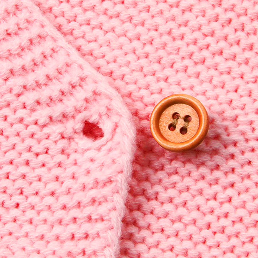 Close-up of a button on the pink knitted bunny rabbit sleep sacks sleeping bags for newborn babies and reborn dolls.