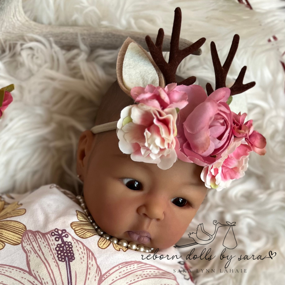 Baby deer antler headbands with faux flowers for reborn dolls and newborn baby photoshoots. Suu Kyi aka Sparrow by Adrie Stoete wearing the Pink with Ears option.