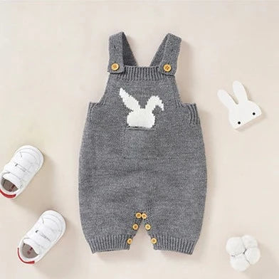 Grey knitted overall shorts for reborn dolls with a white silhouette of a bunny rabbit sticking out of the pocket. 