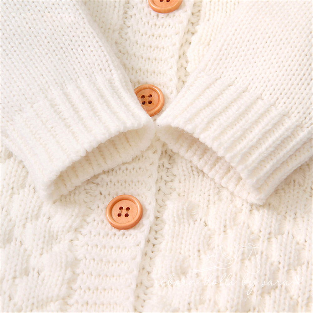 Close-up of the buttons and sleeve cuffs on a creamy white knitted bear romper for reborn dolls.