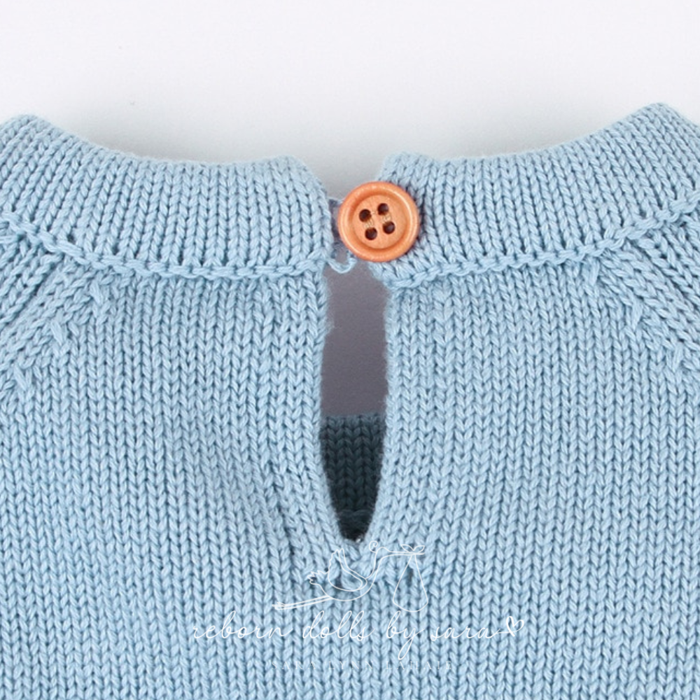 Close-up of the button on the back of the neck on a blue knitted long-sleeve sweater onesie romper for reborn baby dolls.