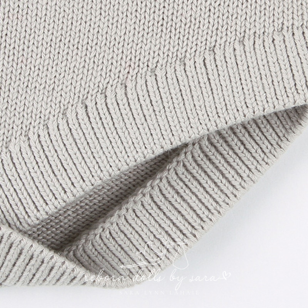 Close-up of the leg opening on a grey knitted long-sleeve sweater onesie romper for reborn baby dolls.