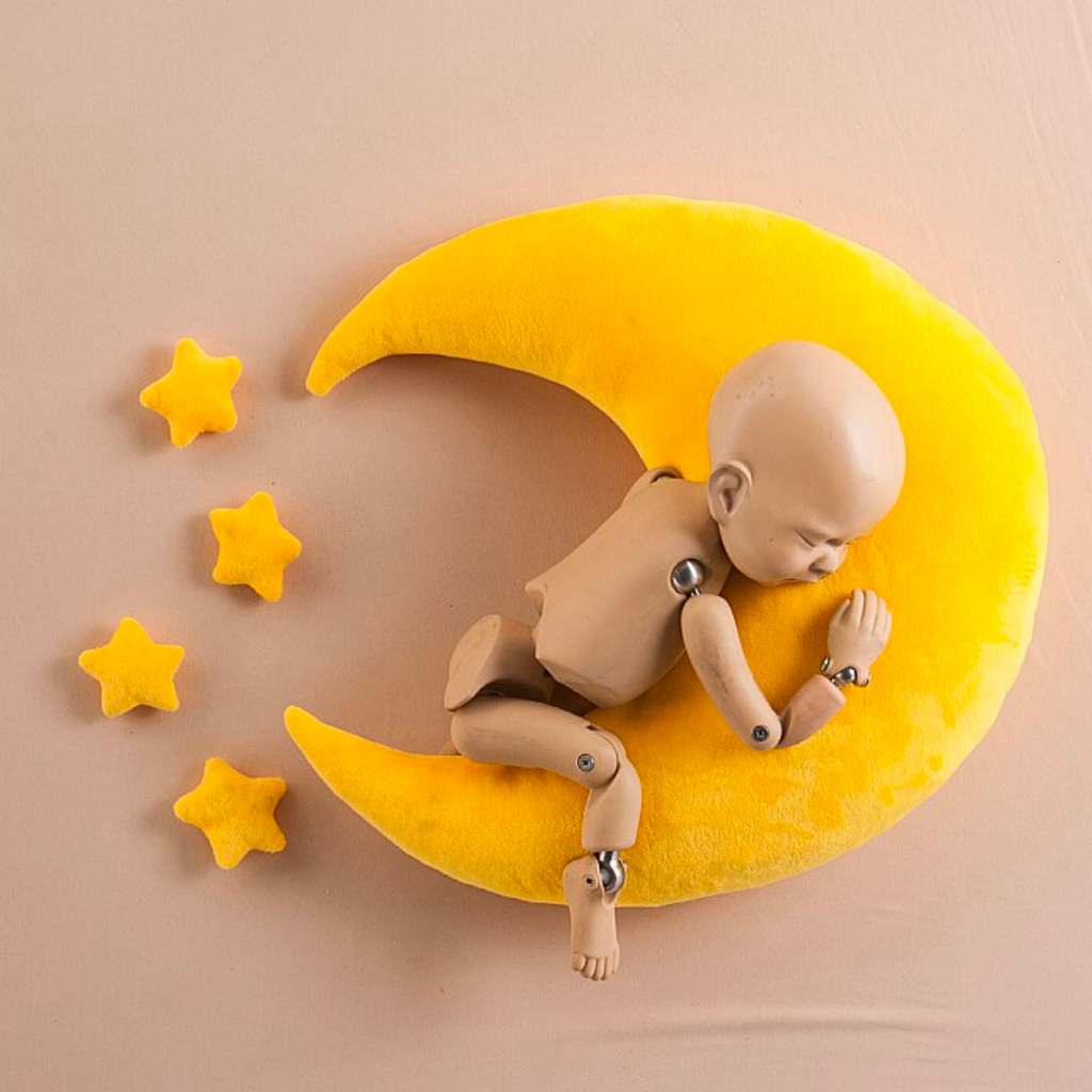Stand-in photography model posing on a yellow flannel moon crescent photography pillow with four stars beside her for newborn and reborn doll photography.