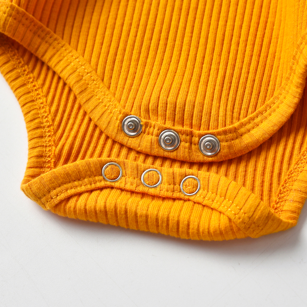 Close-up of the snap crotch buttons on a mustard yellow ribbed onesie and pant set called The Baby Oliver ribbed jogging suit for reborn baby boys and newborn babies.