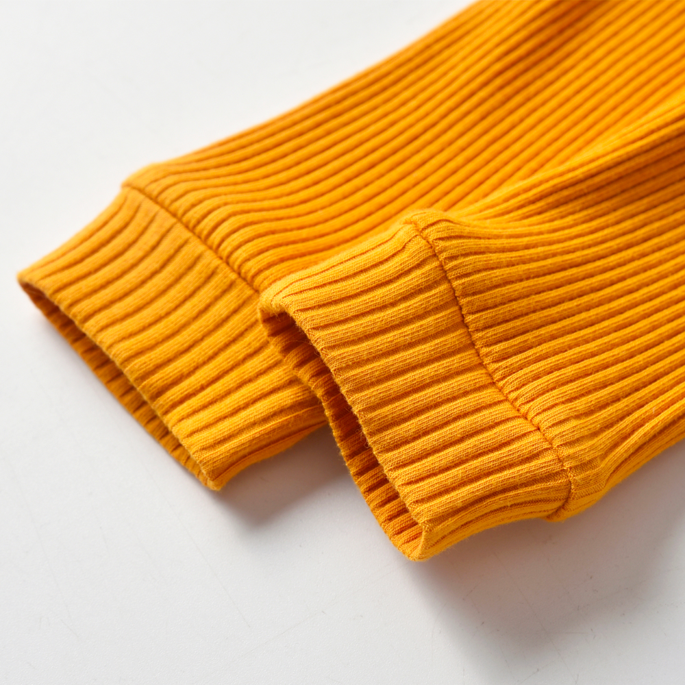 Close-up of the ankles and pant legs of a mustard yellow ribbed onesie and pant set called The Baby Oliver ribbed jogging suit for reborn baby boys and newborn babies.