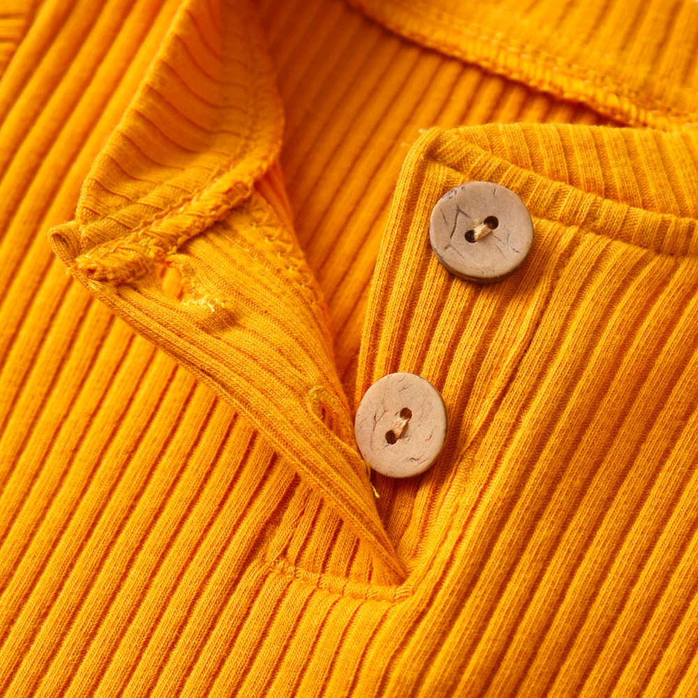 Close-up of the buttons at the chest of a mustard yellow ribbed onesie and pant set called The Baby Oliver ribbed jogging suit for reborn baby boys and newborn babies.