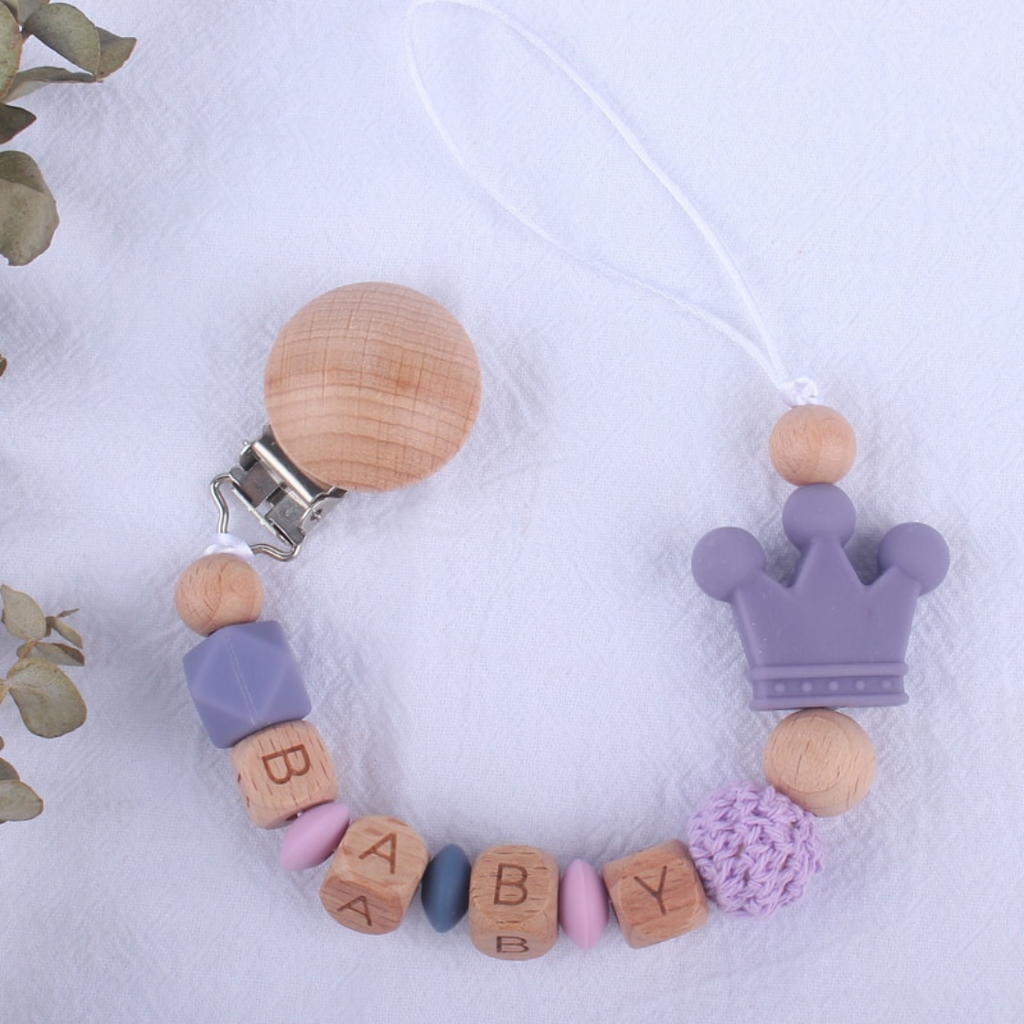 Lavendar, pink, grey and lilac purple personalized silicone pacifier clips with wooden fastener, crown bead, crochet beads, wooden beads with spacers between them, and silicone beads with baby's name for reborn baby dolls.