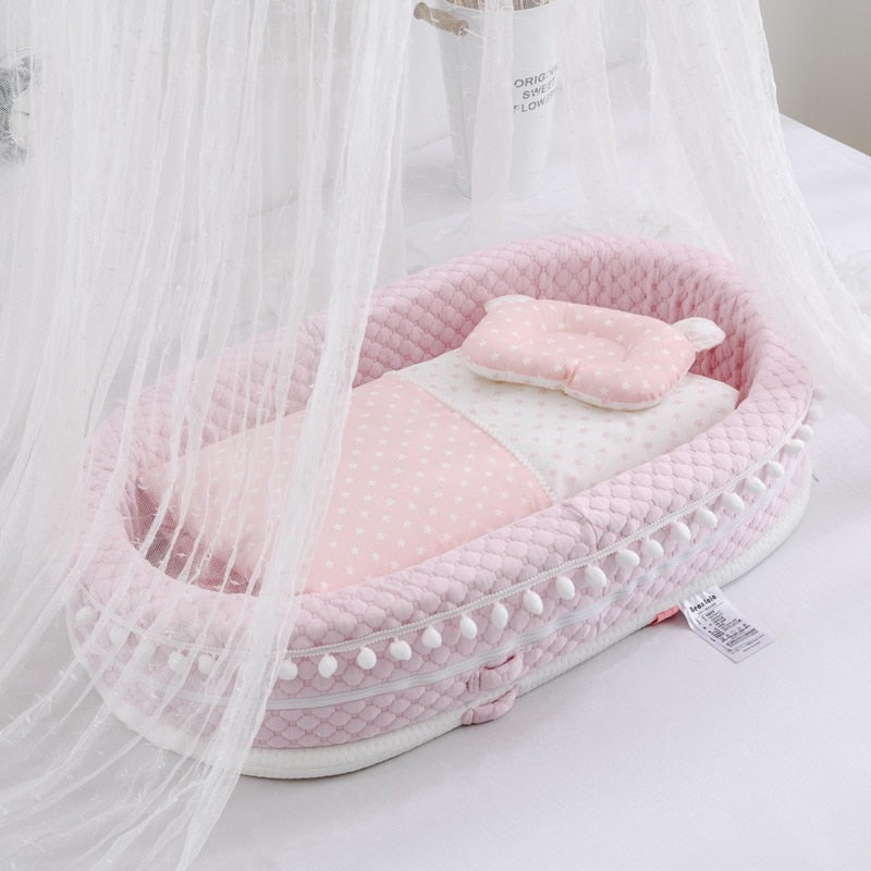 Pink baby nest lounger with pompoms and pink and white star blankets for reborn baby dolls.