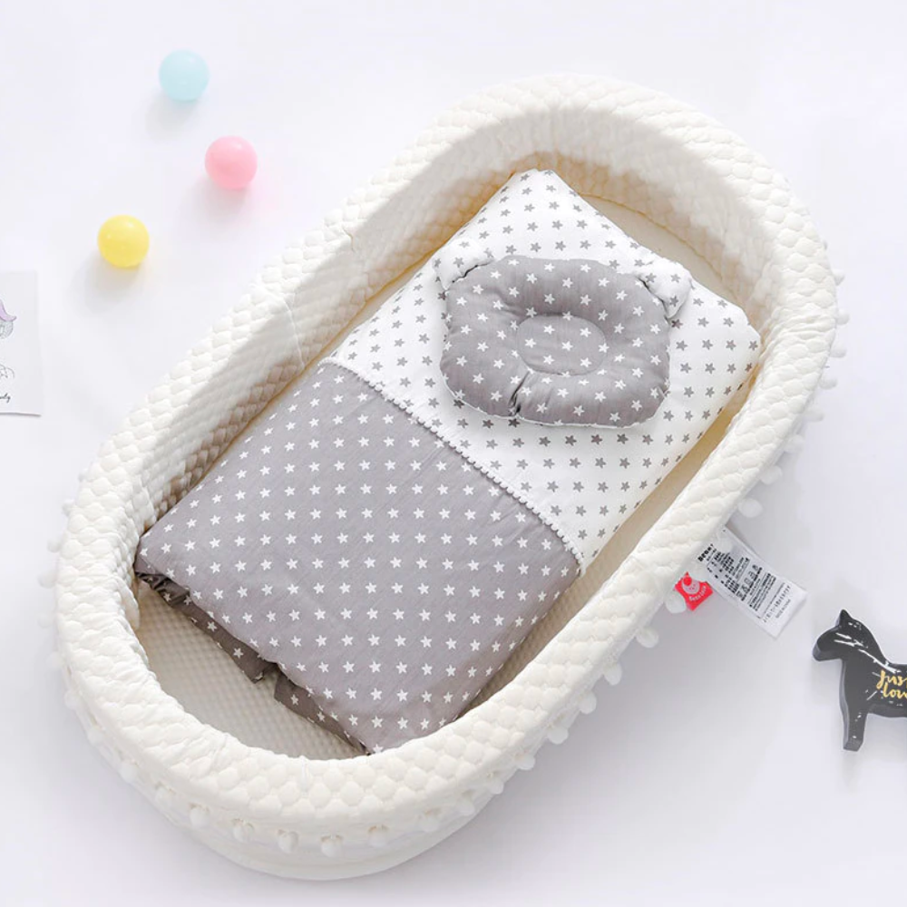White baby nest lounger with pompoms and grey and white star blankets for reborn baby dolls.