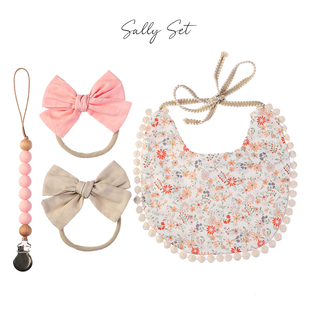 Floral boho bib, a pink bow nylon headband, a beige bow headband, and a pink and wood silicone pacifier clip.