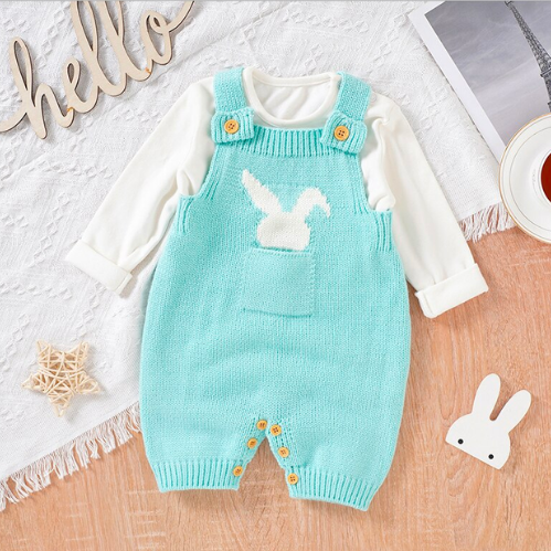 Aqua blue knitted overall shorts for reborn dolls with a white silhouette of a bunny rabbit sticking out of the pocket paired with a white long-sleeve onesie.
