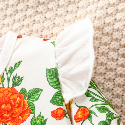 Close-up of the frilly white sleeve that is on a hite long-sleeve onesie with white frills at the sleeve and orange and yellow floral pattern, with green leaves and red berries. Comes with a scarlet red waffle knit dress with straps that button on the inside of the dress and a matching nylon bow headband for reborn baby girls.