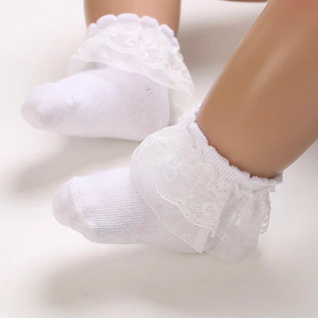 Plain white baby socks with lace frills at the top on a reborn doll.