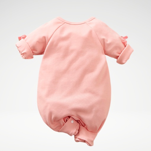 The back of a pink long-sleeve jumpsuit romper featuring a white unicorn with closed eyes and gold hair and the words "unicorns are real" underneath it for reborn baby girl dolls.