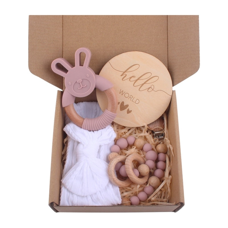 Mauve Bean Paste dusty rose pink blush and Ivory white Five Piece Boho Baby Girl Gift Set and reborn doll box opening with teething ring, headband, milestone card that says hello world, silicone pacifier clip and silicone teething bracelet with wooden rings.