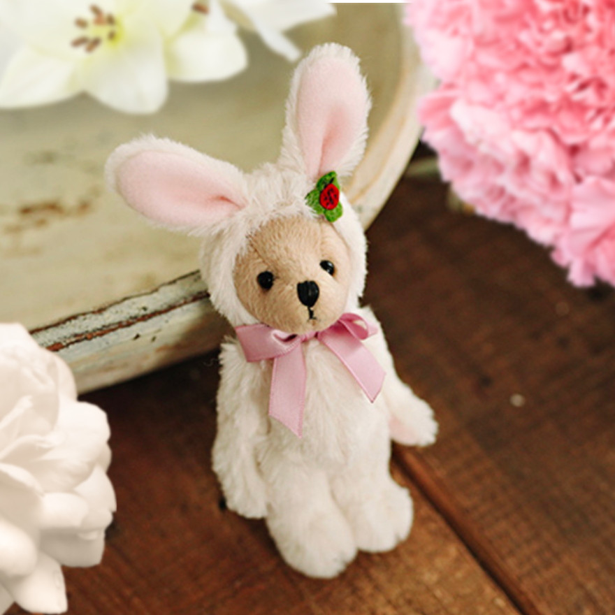 Teddy bear wearing a white bunny rabbit costume with a pink silk bow.  Reborn baby doll teddy bear toys that can be used by newborn photographers as well as newborn photography props.