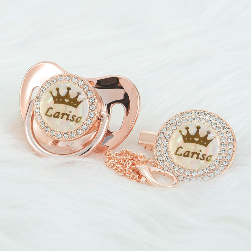 Rose Gold Custom Personalized Pacifiers for Reborn Baby Dolls and Newborn Babies with names, crown, pearlescent backgrounds, and bling. Comes with a pacifier clip in gold.