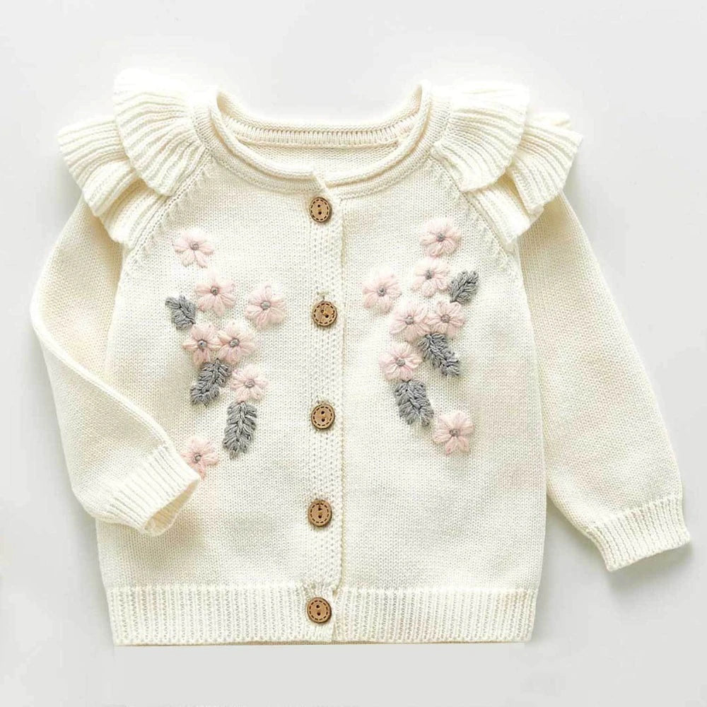 Creamy white knitted cardigan with frilly sleeves, long-sleeves, and buttons down the centre. Has beautiful pink and grey floral embroidery on the chest. Made for newborn baby girls to 3 years old and reborn dolls.