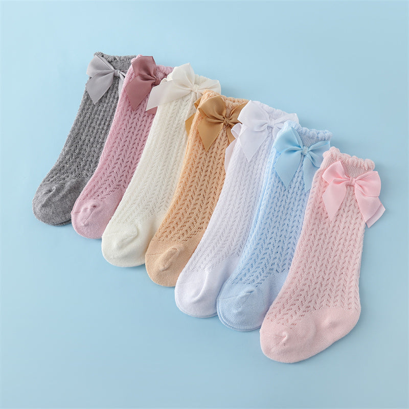 Knee-high cable knit socks with bow on the top and ruffle detail near the knee.