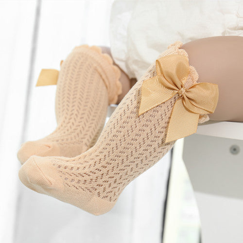 Yellow knee-high cable knit socks with bow on the top and ruffle detail near the knee.