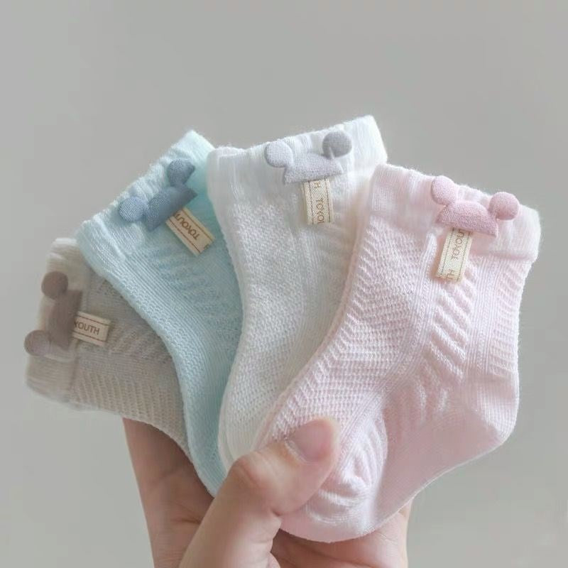 Hand holding four pairs of Mickey Mouse reborn doll, newborn baby, and cuddle baby cotton socks in beige, blue, whit and pink.
